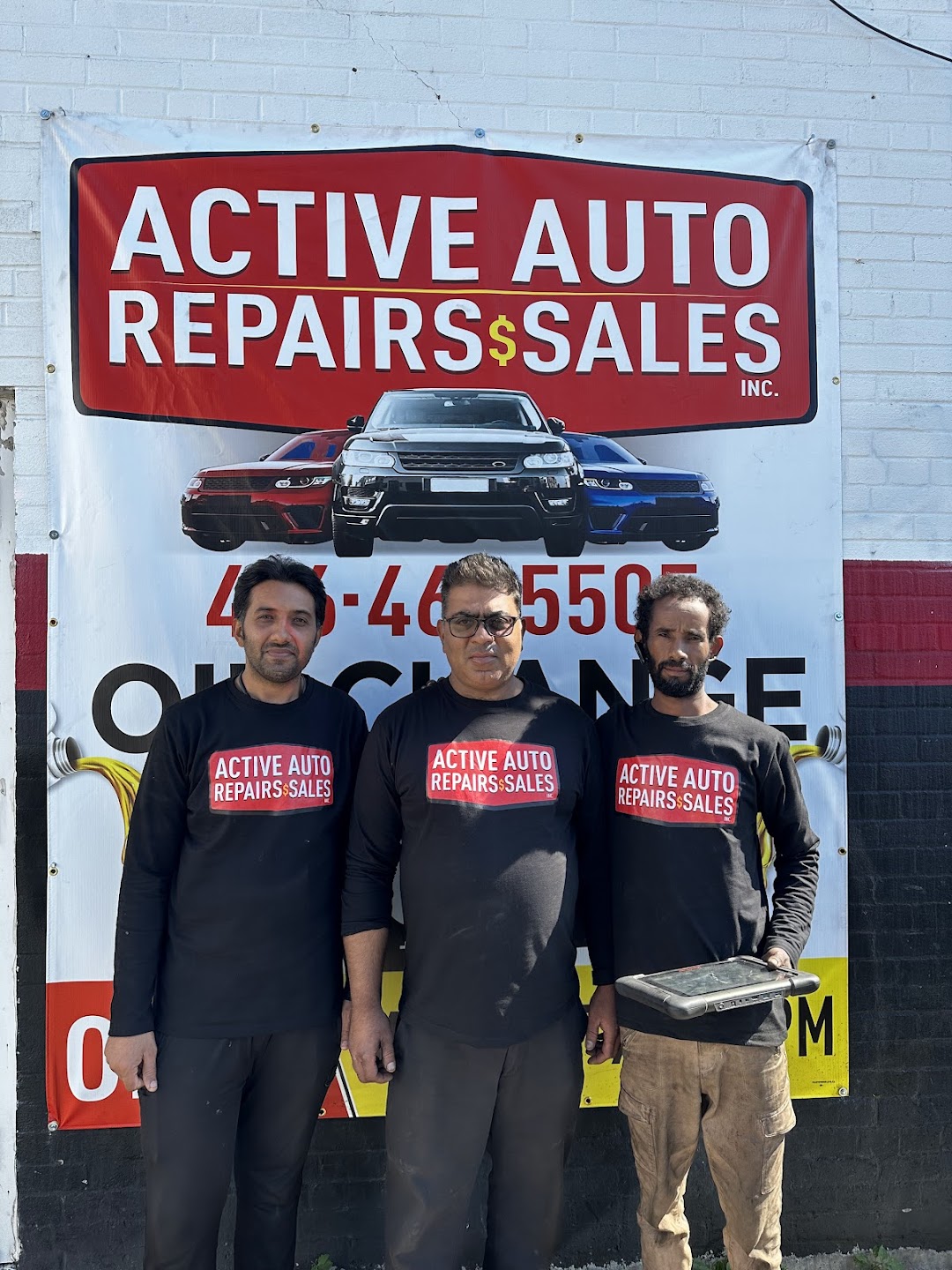 Active Auto Repairs team members in front of shop banner